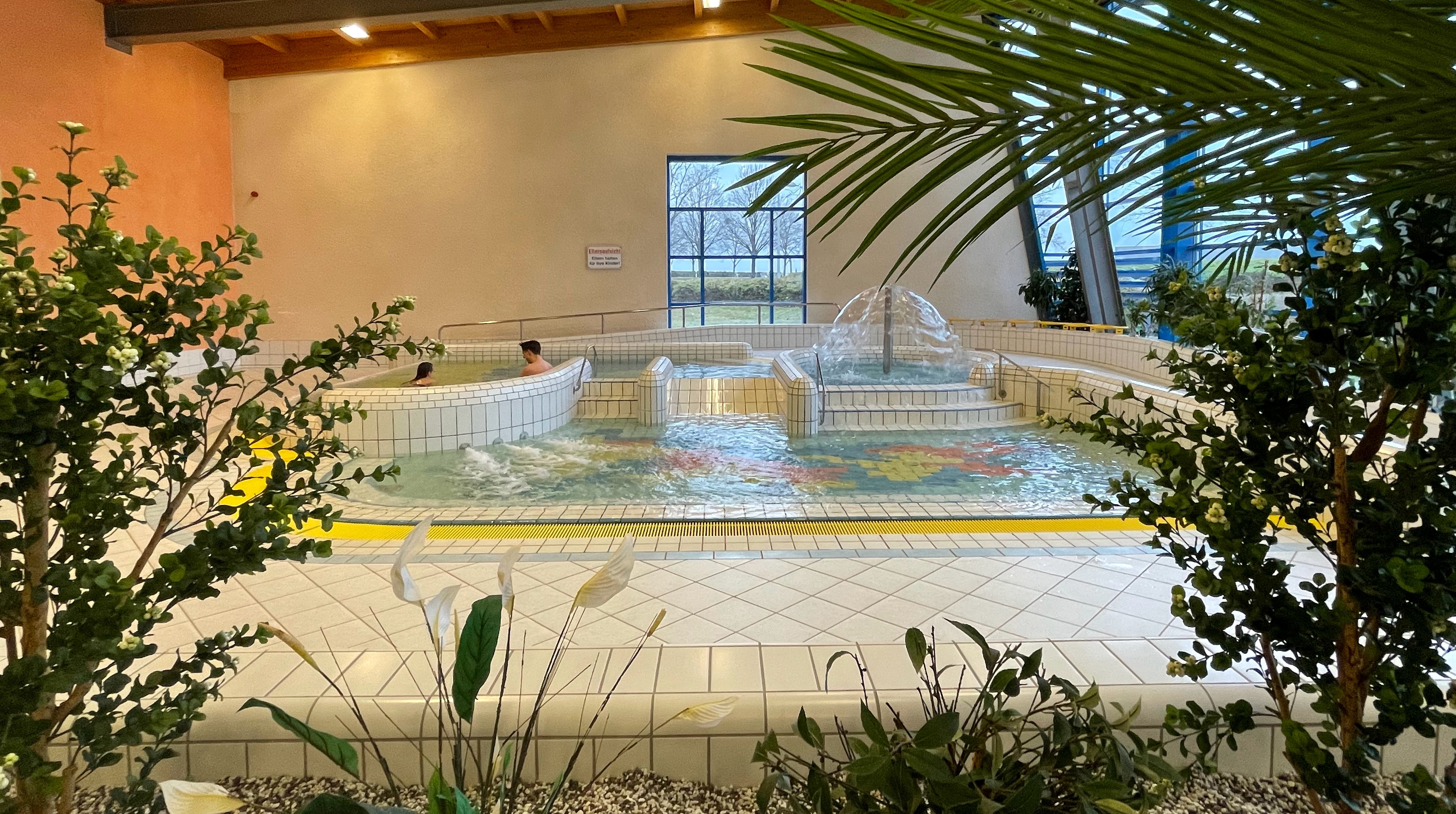 Planschbecken mit einer kleinen Rutsche, einem Wasserpilz, einem Luftsprudler und einer Massagedüse